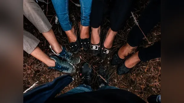 Overhead view of a group standing in a circle, their shoes together on the ground.